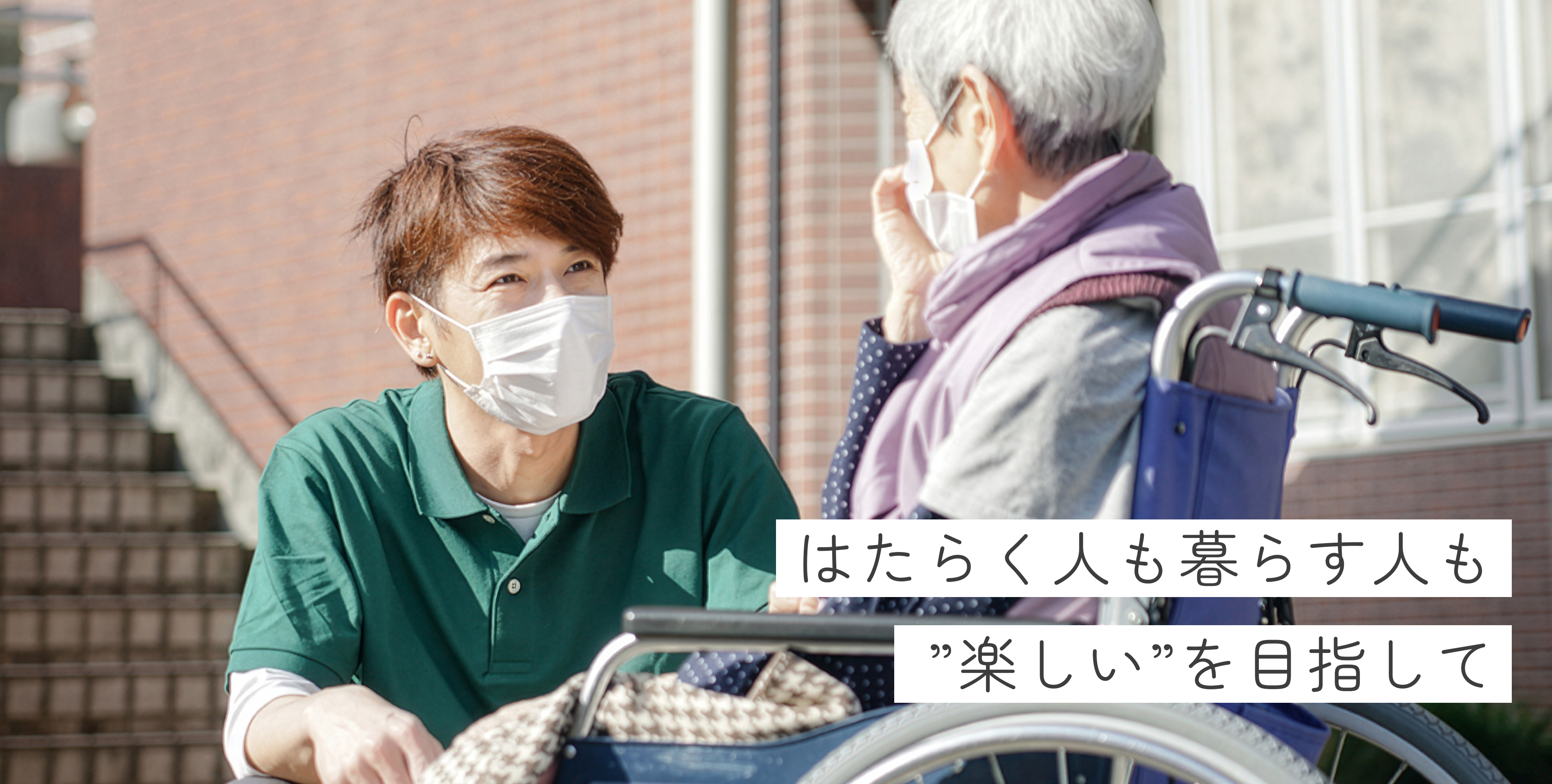 車いすに座っているご利用者の女性と、目線を合わせて話している介護職の男性