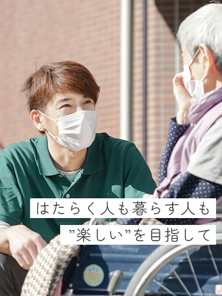 車いすに座っているご利用者の女性と、目線を合わせて話している介護職の男性