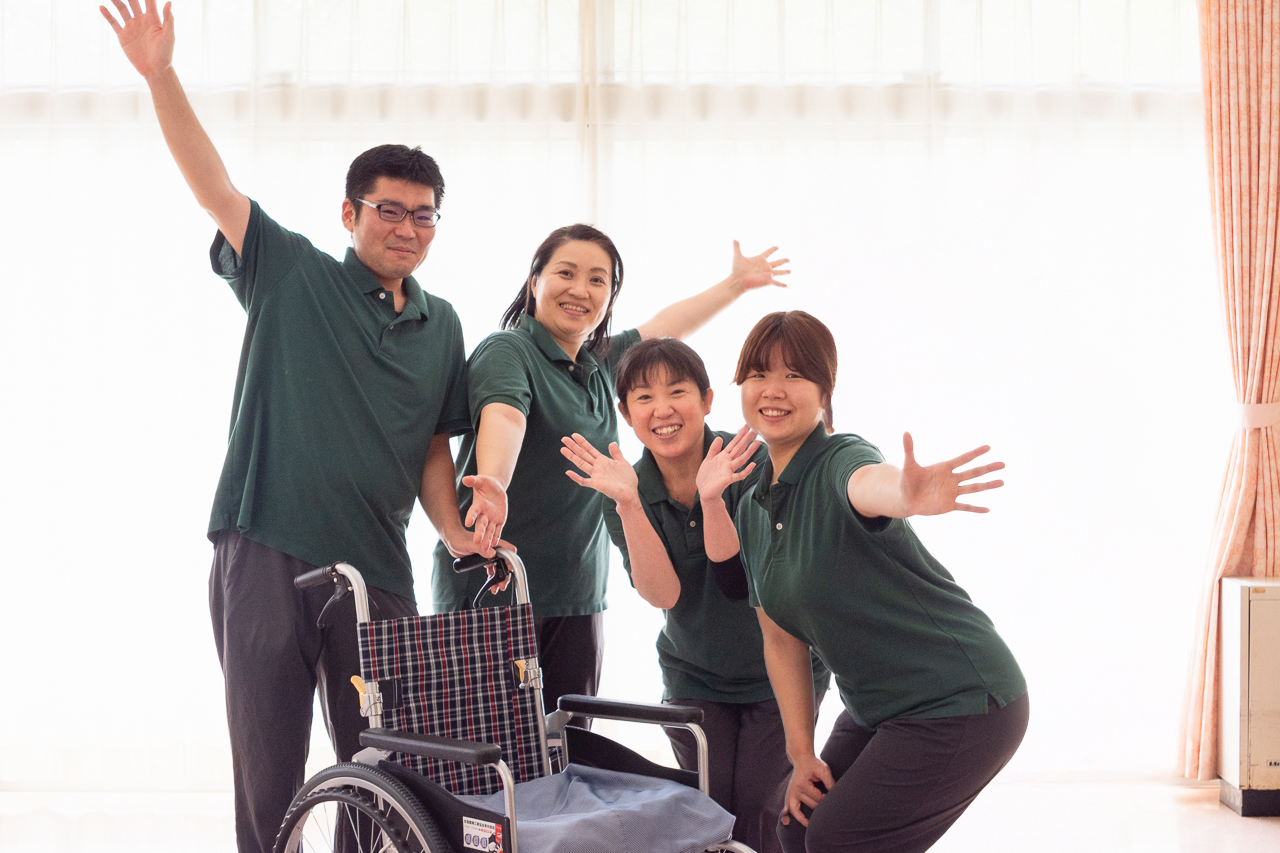コスモホームの介護職員4人が手を広げて笑っている写真